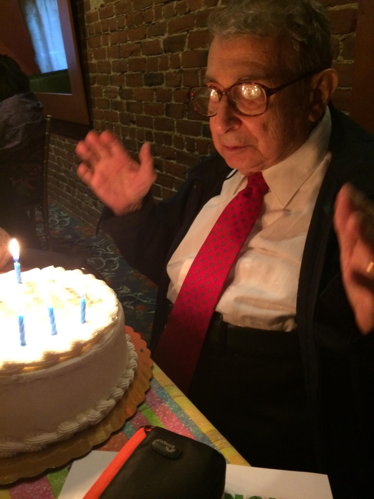 Alan R Pearlman about to blow out candles of the cake at his 90the birthday party.