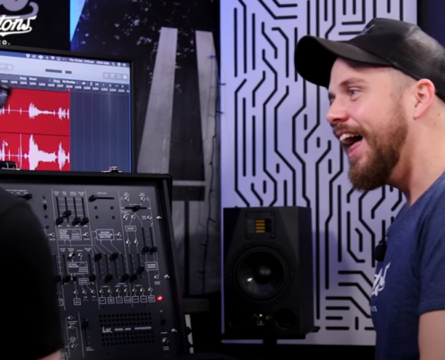 a man with beard and baseball hat looks excited about a synthesizer